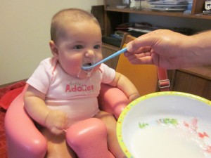 Getting messy while eating baby cereal.